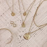Photo of various necklaces and other jewelry designs laid on a wood table.