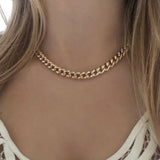 A female model wearing a chunky gold necklace.