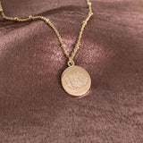Pretty necklace featuring a dainty gold beaded chain and a round medal pendant engraved with a lotus design. By Kurafuchi.