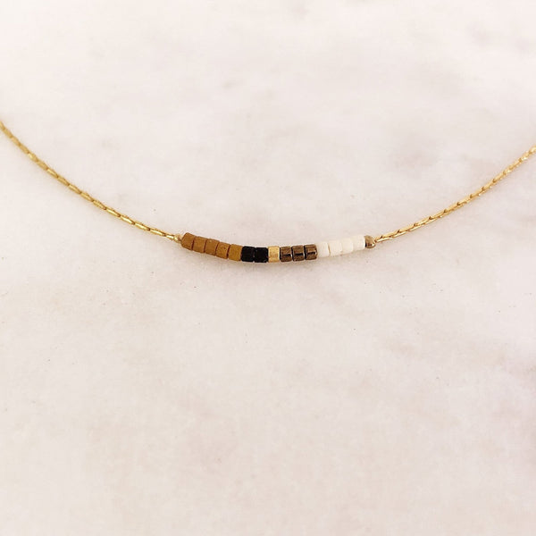 Minimalist necklace made of a dainty gold chain decorated with tiny beads in a colorful pattern. Designed by Kurafuchi.