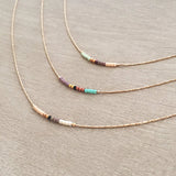 Minimalist necklace made of a dainty rose gold chain decorated with tiny beads in a colorful pattern. Designed by Kurafuchi.