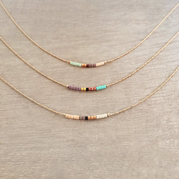 Minimalist necklace made of a dainty rose gold chain decorated with tiny beads in a colorful pattern. Designed by Kurafuchi.