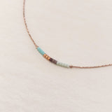 Minimalist necklace made of a dainty gold chain decorated with tiny beads in a colorful pattern. Designed by Kurafuchi.