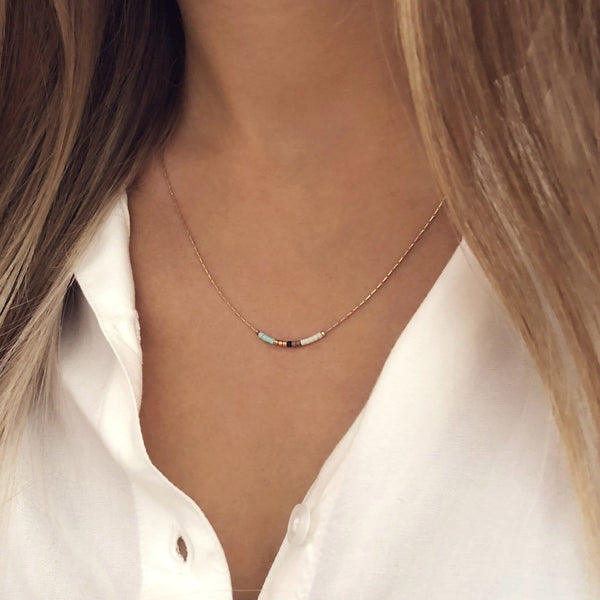 A female model wearing a minimalist dainty necklace by Kurafuchi Jewelry.