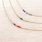 Minimalist necklaces made of a thin gold chain decorated with tiny beads in a colorful pattern. Designed by Kurafuchi.