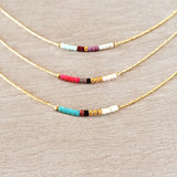 Minimalist necklaces made of a thin gold chain decorated with tiny beads in a colorful pattern. Designed by Kurafuchi.