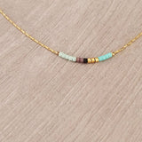 Minimalist necklace made of a thin gold chain decorated with tiny beads in a colorful pattern. Designed by Kurafuchi.