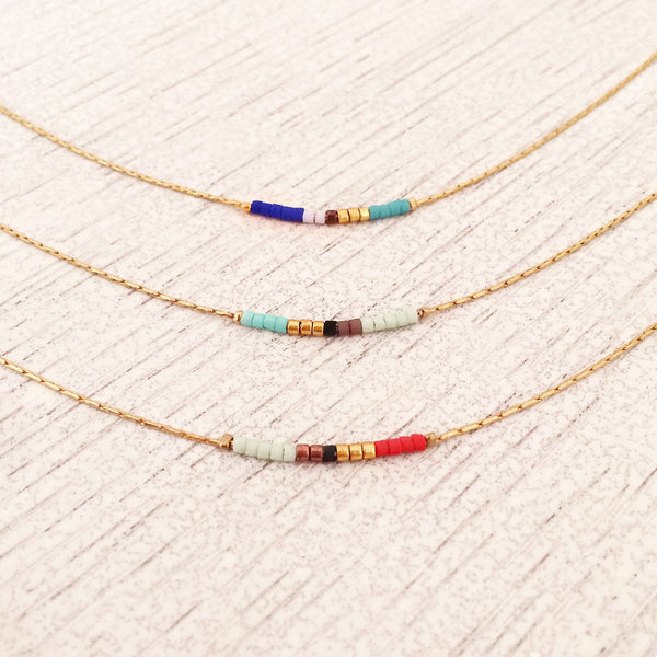 Minimalist necklaces made of a dainty gold chain decorated with tiny beads in a colorful pattern. Designed by Kurafuchi.