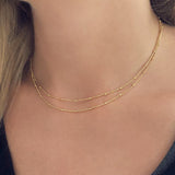 A female model wearing a gold double-strand chain necklace by Kurafuchi Jewelry.