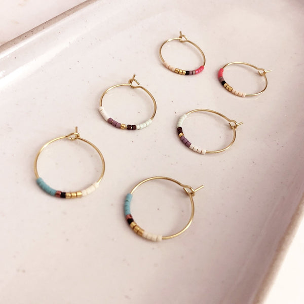 Dainty wire hoops decorated with little beads in multicolor patterns. The hoop diameter is 20mm. By Kurafuchi.