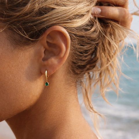 Lovely small gold hoops, each decorated with a teardrop-shaped green crystal zircon.