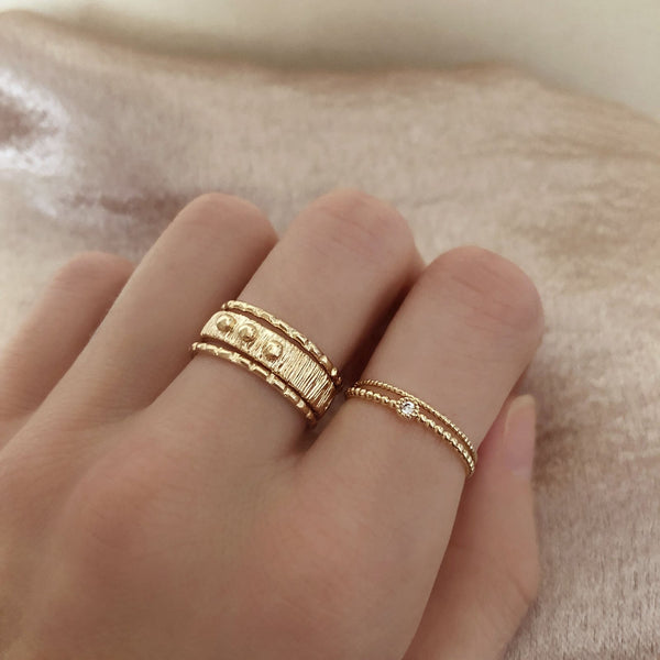 A female model’s hand showcasing a layered look of multiple gold rings over several fingers.
