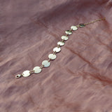 Gold ankle bracelet made of a series of hammered discs attached together.