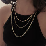 A female model wearing a combined look of three chain necklaces in layered lengths.