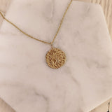 A photo of a gold pendant necklace. The round medal features an eye of Horus egyptian symbol and measures 15mm in diameter.