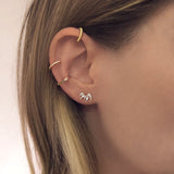A female model’s ear featuring gold stud earrings, hoops and ear cuffs.