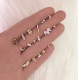 A model’s hand showcasing various gold stud earring designs, some with crystals.