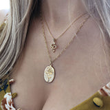 A female model wearing a layered look of gold pendant necklaces.