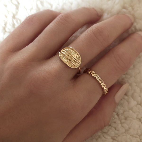 A female model’s hand showcasing a layered look of multiple gold rings over several fingers.