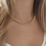 A female model wearing a chunky gold necklace.