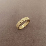 Textured gold band ring with three little beads in its middle.