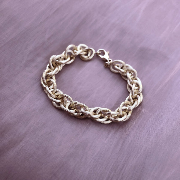 Chunky gold bracelet made of a thick chain of textured links interlaced. By Kurafuchi.