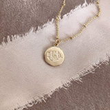 Pretty necklace featuring a dainty gold beaded chain and a round medal pendant engraved with a lotus design. By Kurafuchi.