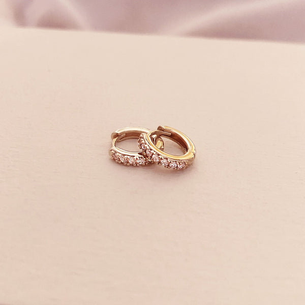 A pair of small gold hoop earrings paved with little zircon crystals. By Kurafuchi.