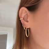 A female model’s ear featuring several Kurafuchi gold stud earrings, hoops and an ear cuff.