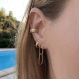 A female model’s ear showcasing several Kurafuchi gold stud earrings, hoops and an ear cuff.