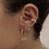 A female model’s ear showcasing several gold stud earrings, hoops and an ear cuff, all by Kurafuchi.