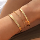 A female model’s wrist wearing a layered look of multiple Kurafuchi gold bracelets and cuffs in various designs.