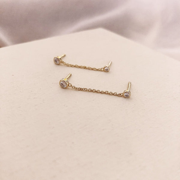 Double stud earrings made of a dainty gold chain finished by a zircon crystal on each end. By Kurafuchi.