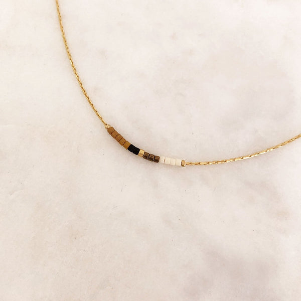 Minimalist necklace made of a thin gold chain decorated with tiny beads in a multicolor pattern. Designed by Kurafuchi.