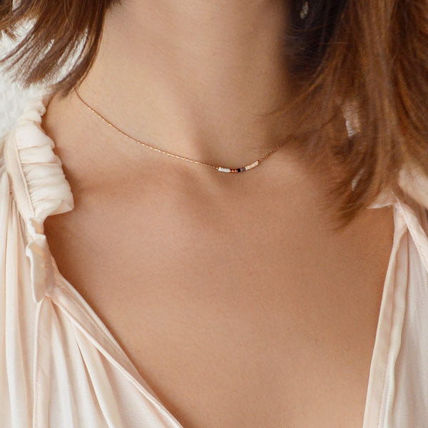 A female model wearing a minimalist rose gold dainty necklace by Kurafuchi Jewelry.