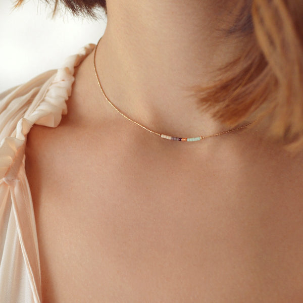 A female model wearing a minimalist rose gold dainty necklace by Kurafuchi Jewelry.