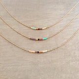 Minimalist necklace made of a dainty rose gold chain decorated with tiny beads in a colorful pattern. Designed by Kurafuchi.