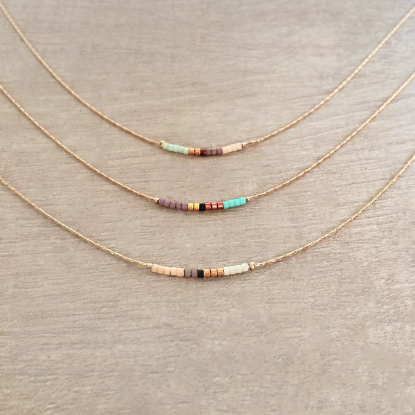 Minimalist necklace made of a dainty rose gold chain decorated with tiny beads in a colorful pattern. Designed by Kurafuchi.