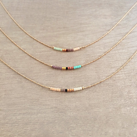 Minimalist necklace made of a dainty rose gold chain decorated with tiny beads in a colorful pattern. Designed by Kurafuchi.