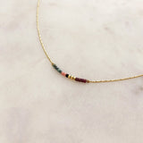 Minimalist necklace made of a dainty gold chain decorated with tiny beads in a colorful pattern. Designed by Kurafuchi.