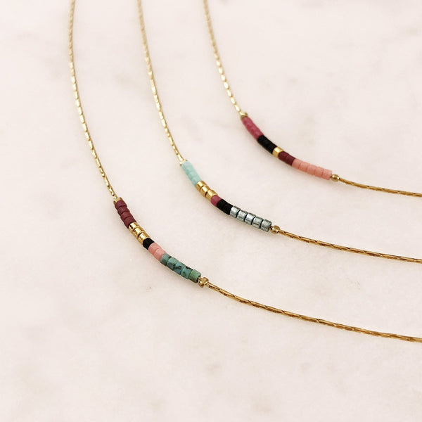 Minimalist necklace made of a thin gold chain decorated with tiny beads in a colorful pattern. Designed by Kurafuchi.