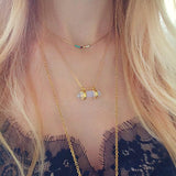 A female model wearing a layered look of gold pendant necklaces.