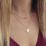 A female model wearing a layered look of gold Kurafuchi necklaces.