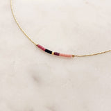 Minimalist necklace made of a thin gold chain decorated with tiny beads in a colorful pattern. Designed by Kurafuchi.