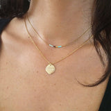 A female model wearing a layered look of gold Kurafuchi necklaces.