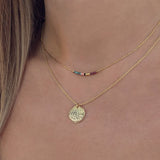A female model wearing a layered look of gold Kurafuchi necklaces.