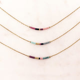 Minimalist necklaces made of a dainty gold chain decorated with tiny beads in a colorful pattern. Designed by Kurafuchi.