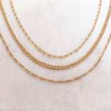 A photo of three gold chain necklaces laid flat.