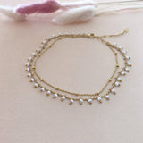 Double gold ankle bracelet made of a chain beaded with white beads and a simple dainty chain.