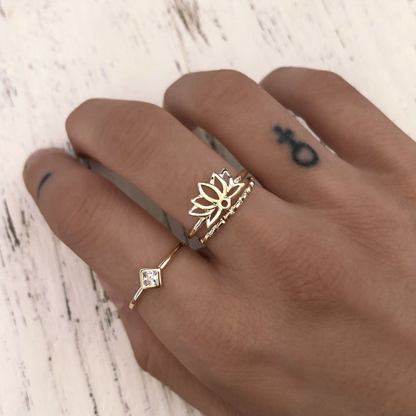 A female model’s hand showcasing a layered look of multiple Kurafuchi gold rings over several fingers.